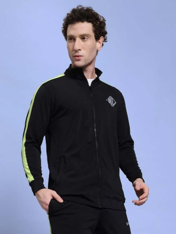 Person wearing a HIGH PERFORMANCE JACKET IN BLACK with neon accents against a blue background.