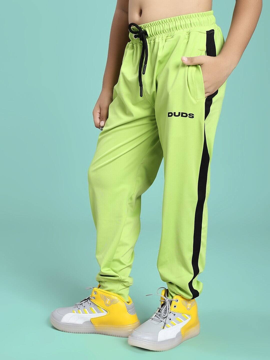 Child wearing HIGH PERFORMANCE JOGGER FOR BOYS AND GIRLS NEON GREEN with yellow sneakers, showcasing comfortable athletic fit.