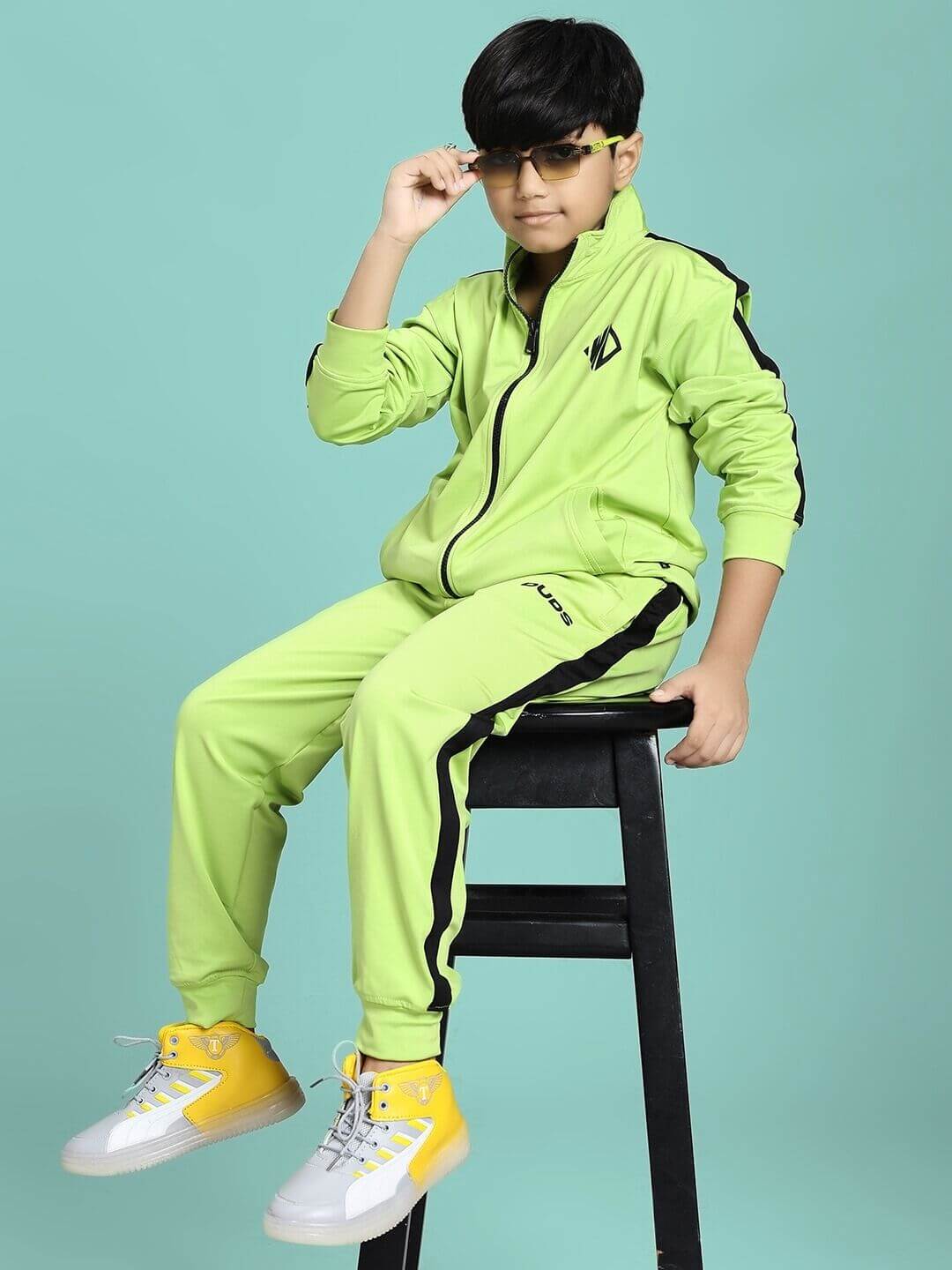 Boy wearing HIGH PERFORMANCE CO-ORD SET FOR BOYS AND GIRLS NEON GREEN, sitting confidently on a stool, showcasing sporty and stylish design.