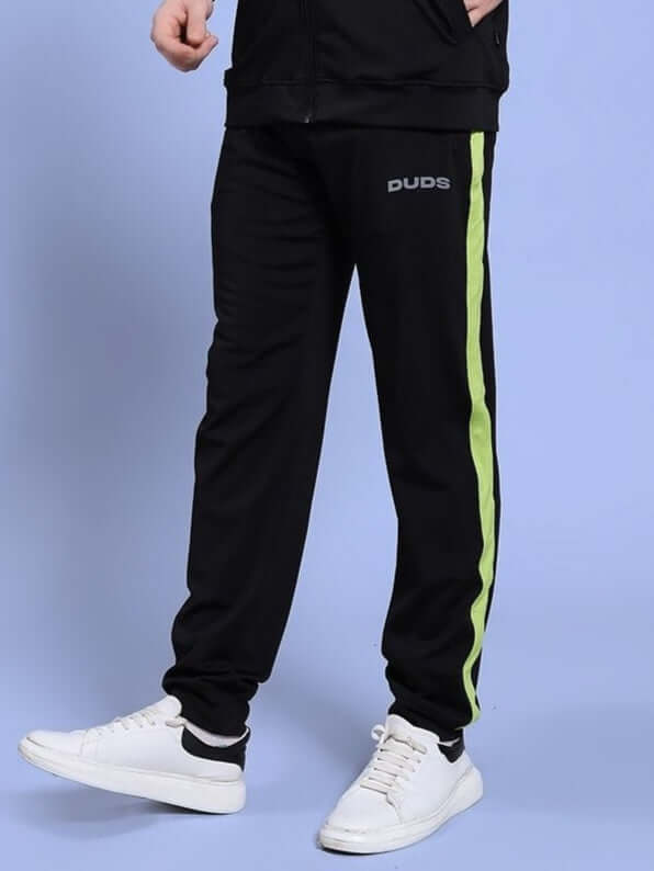 Person wearing HIGH PERFORMANCE RELAXED FIT JOGGER BLACK with green stripe, showcasing comfort and style indoors.