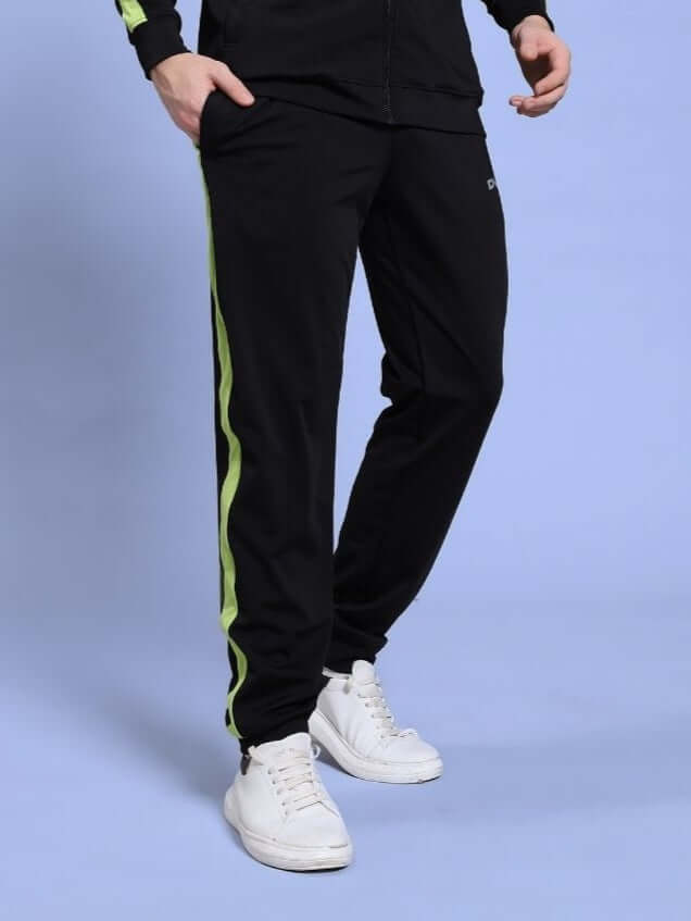 Man wearing HIGH PERFORMANCE RELAXED FIT JOGGER BLACK with green stripe, showcasing flexibility and comfort.