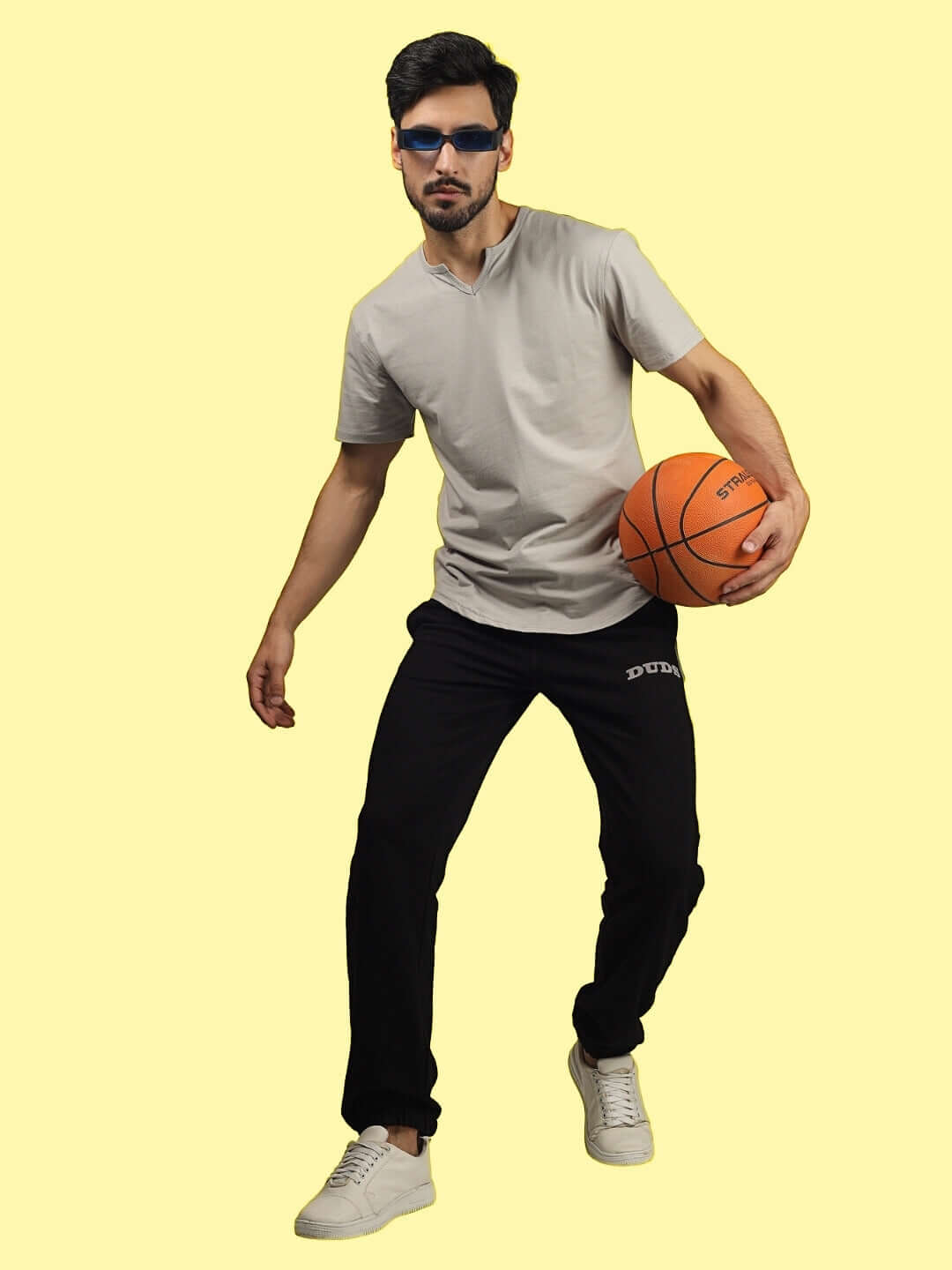 Model wearing HIGH POINT CONTRAST JOGGERS in black-grey, holding a basketball, showcasing DUDS' made-to-order craftsmanship and custom fit options.