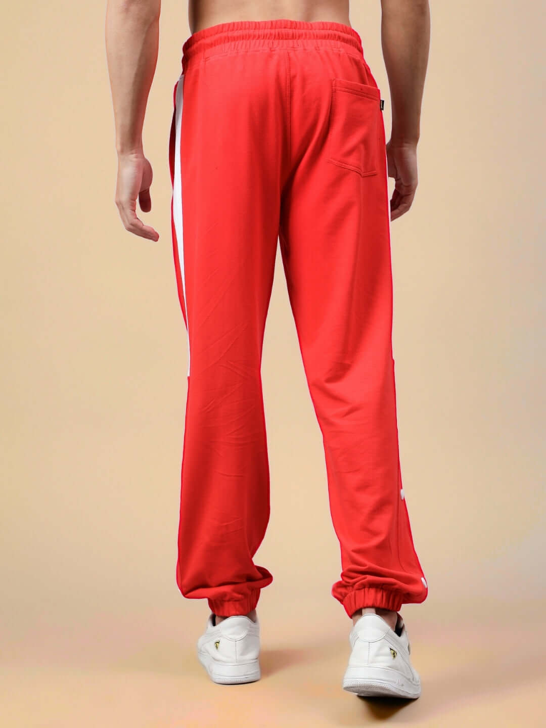 Model wearing red and white High Point Contrast Joggers from DUDS, showcasing rear view and elastic cuffs on a beige background.