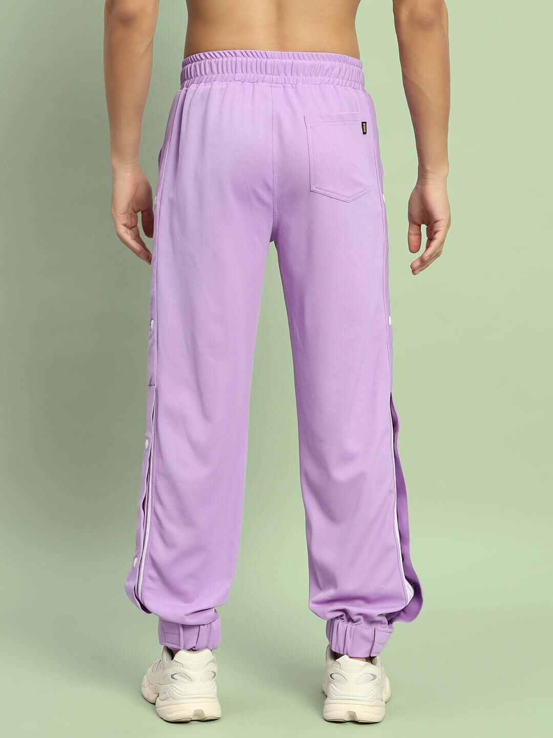 Lavender hip hop joggers with elastic waistband and ankle cuffs, showcased from the back, worn by a model on a light green background.