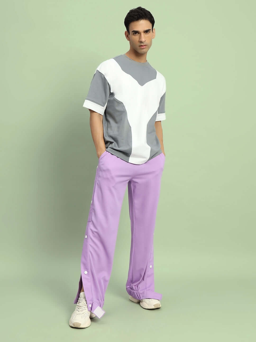 Model wearing lavender hip hop joggers by DUDS, stylish casual wear with custom fit option, standing against a light green background.
