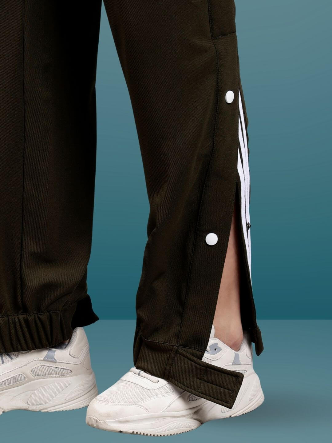 HIP HOP JOGGERS in military green, featuring button details and a stylish fit, paired with white sneakers on a teal background.