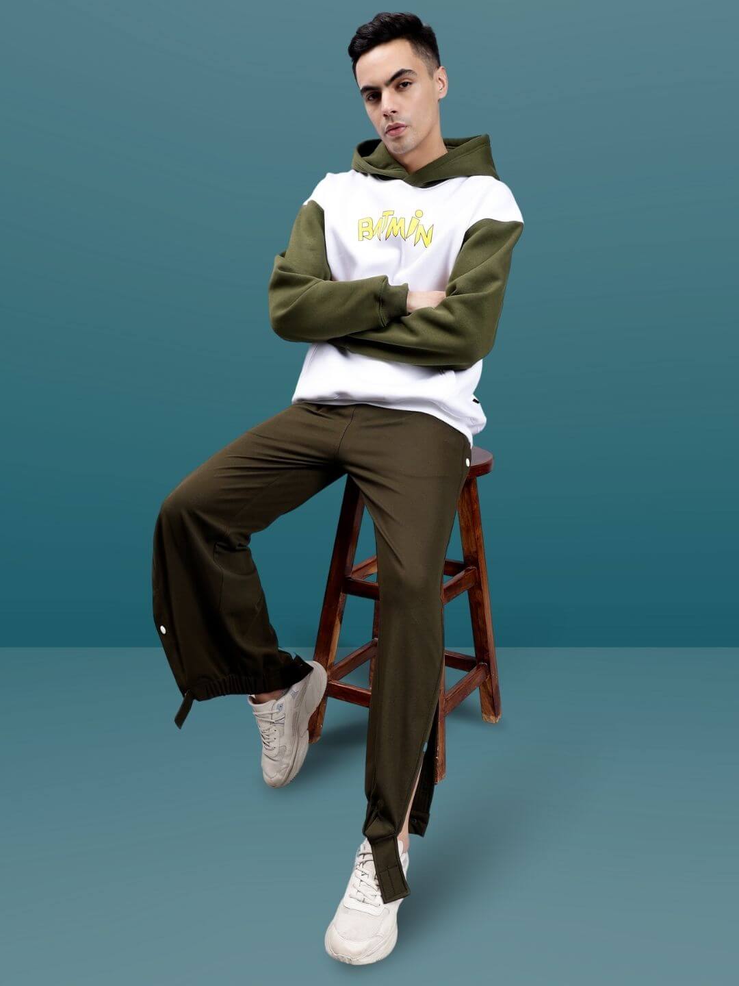 Model wearing military green hip hop joggers with white sneakers and hoodie, showcasing relaxed streetwear style.