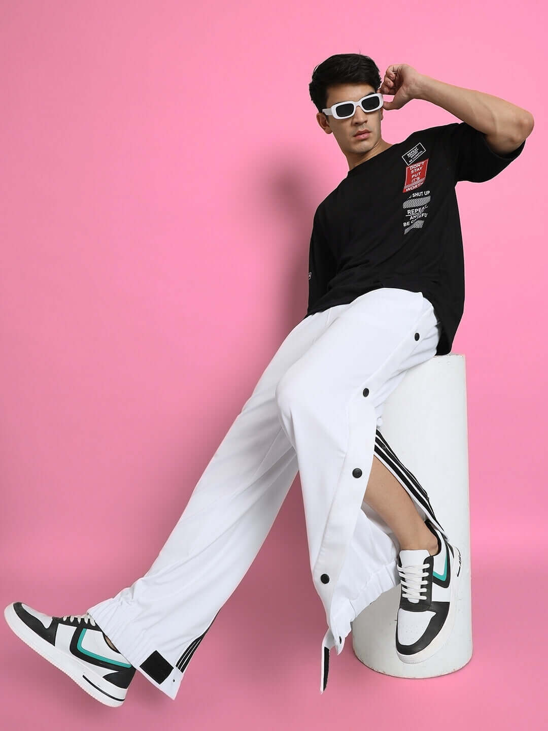 Model wearing HIP HOP JOGGERS in white with black shirt and sneakers, posing against a pink background.