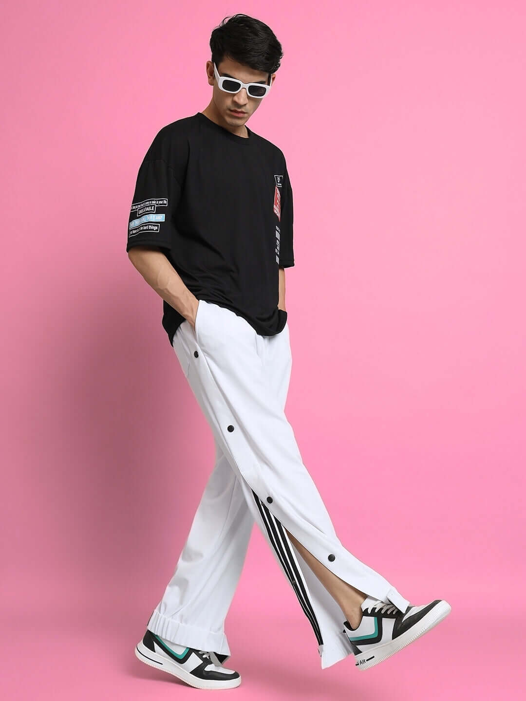 Model wearing Hip Hop Joggers in white with decorative buttons, paired with a black t-shirt and trendy sneakers against a pink background.
