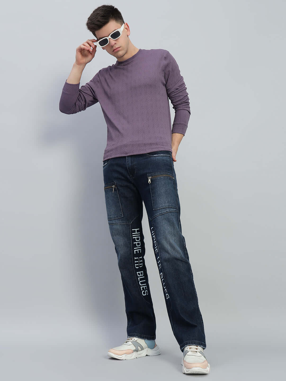 Model wearing Hippie Blue regular fit denim jeans with purple sweater and sunglasses, showcasing a casual stylish outfit.