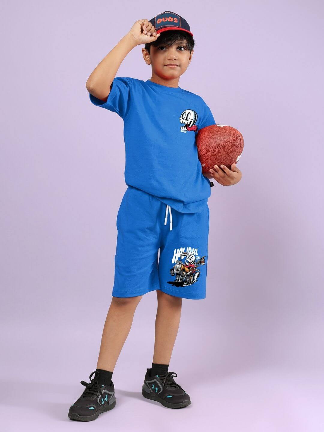 Boy wearing Holiday Time Rider Print Co-ord for Boys and Girls Blue, holding a football.