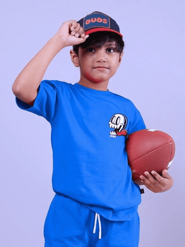 Child wearing HOLIDAY TIME RIDER PRINT T-SHIRT FOR BOYS AND GIRLS BLUE, holding a football, adding playful style.