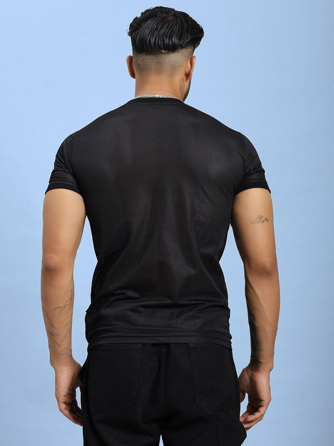 Back view of a model wearing HOLO BLACK MESH REGULAR FIT T-SHIRT BLACK, showcasing mesh panel design, ideal for style and ventilation.