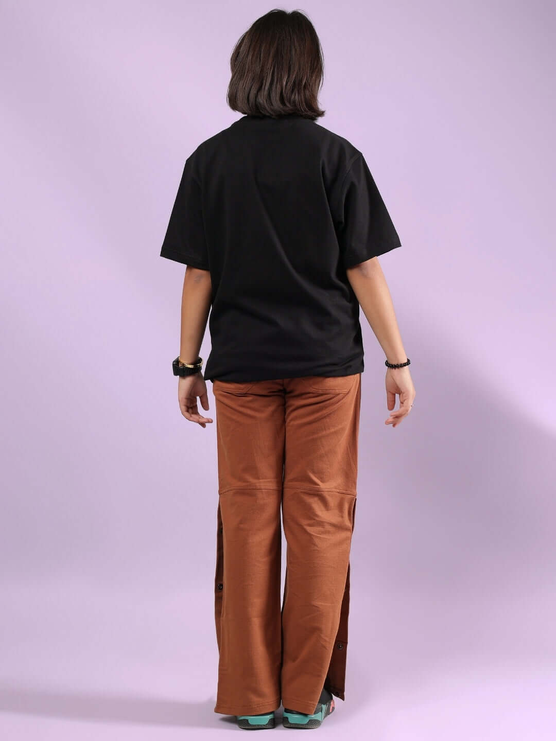 Child wearing HONEY BUNNY CO-ORD FOR BOYS & GIRLS BLACK-BROWN outfit, black top and brown pants, standing back view against purple background.