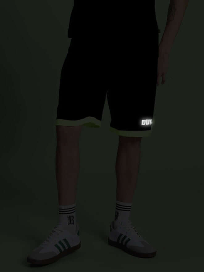 Person wearing HOOKUP REFLECTOR REGULAR FIT SHORTS BLACK with reflective details at night.