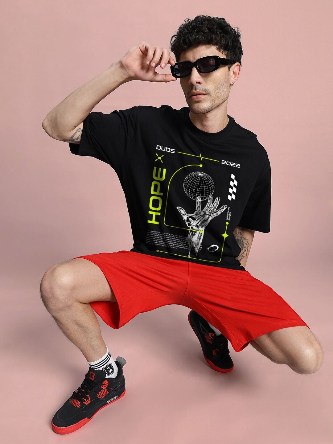 Model wearing HOPE PRINTED OVERSIZED CO-ORD SET BLACK RED with graphic t-shirt and red shorts, showcasing streetwear style.