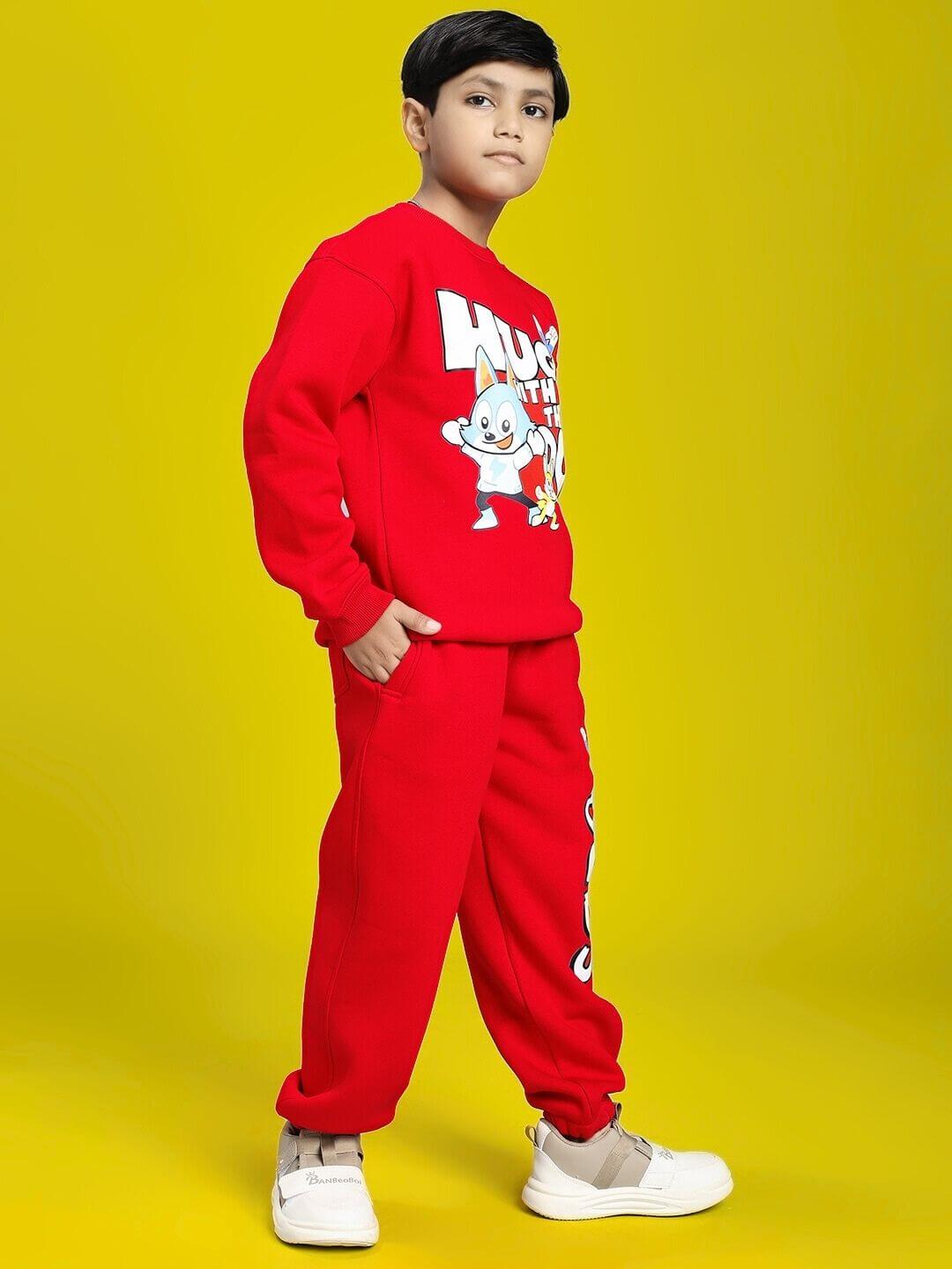 Child wearing HUG WITH THE DOG FLEECE CO-ORD FOR BOYS AND GIRLS RED, showcasing cozy red outfit with dog graphic on vibrant yellow background.