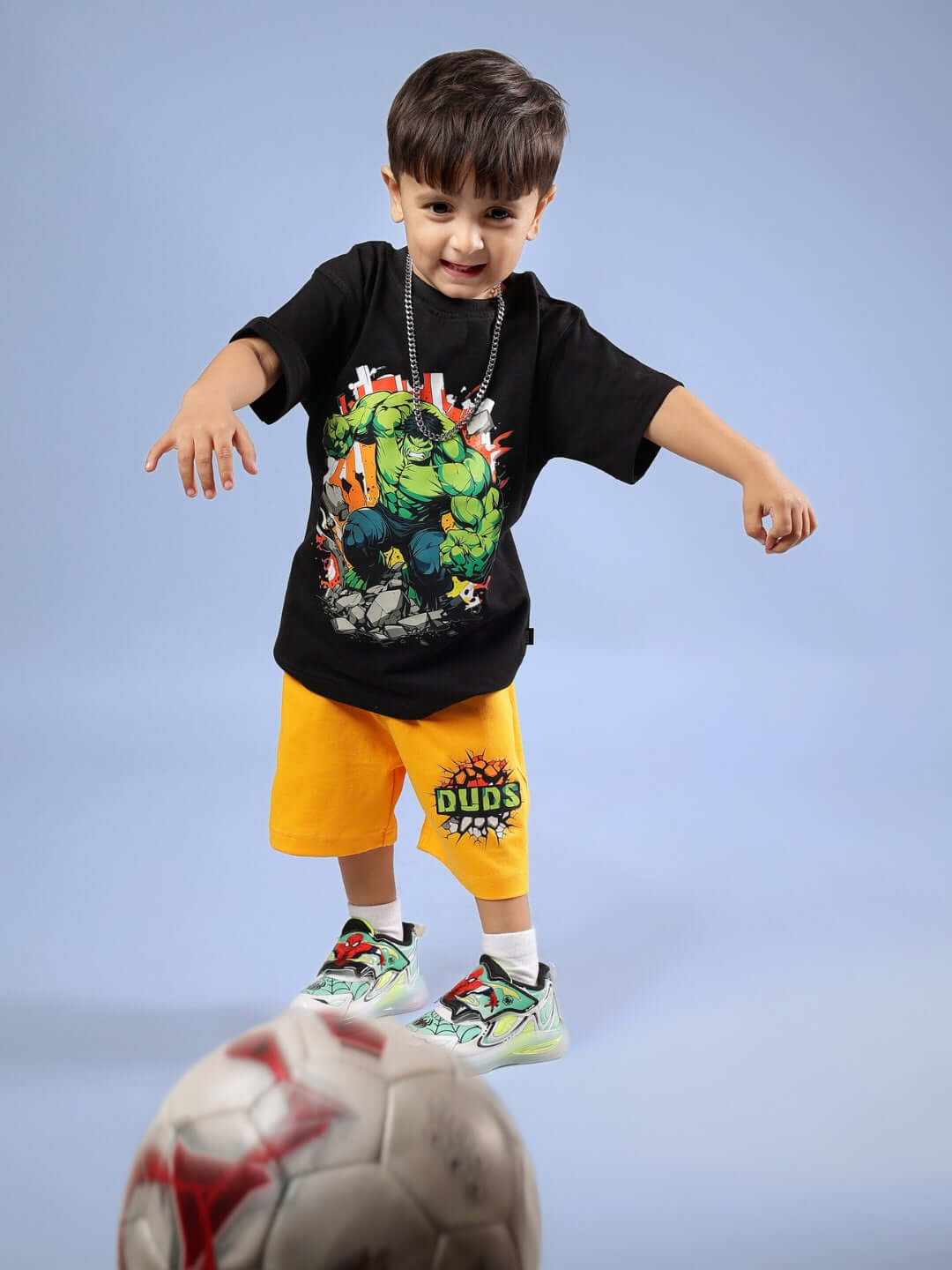 Child wearing HULK CO-ORD FOR BOYS & GIRLS BLACK-YELLOW playing with a soccer ball.