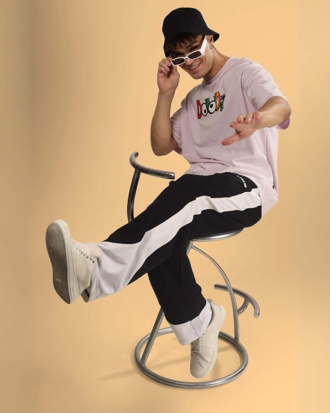 Man stylishly seated wearing HURTLE BAGGY JOGGERS in black and white with modern casual outfit.