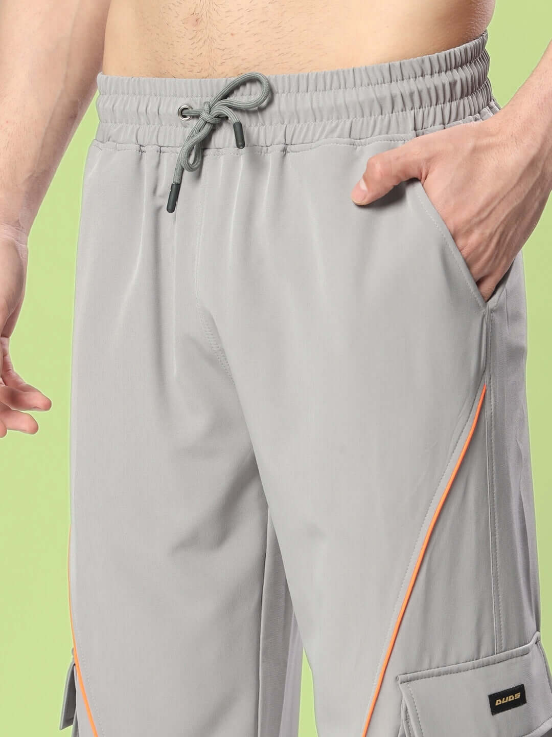 Hypebeast grey cargo pants with neon orange accents, featuring adjustable drawstring and pockets, perfect for streetwear enthusiasts.