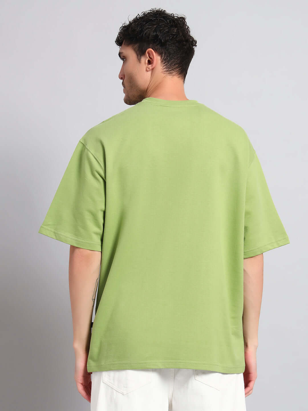Back view of a model wearing IKON BUTTERFLY T-SHIRT GREEN MEN, showcasing its vibrant green color and casual streetwear style.
