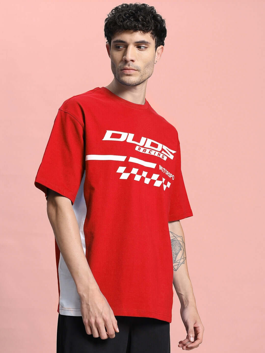 Man wearing INDY OVER-SIZED CLASSIC T-SHIRT RED, premium cotton fabric, displaying timeless streetwear style against pink background.