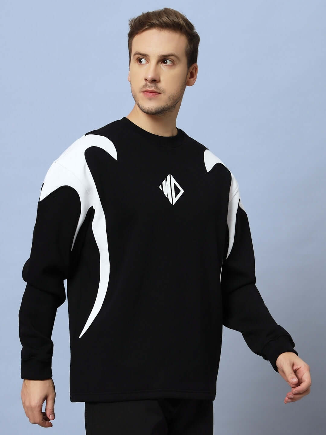 Model wearing INFINITY SAGA OVERSIZED FLEECE SWEATSHIRT BLACK with white accents against a blue background