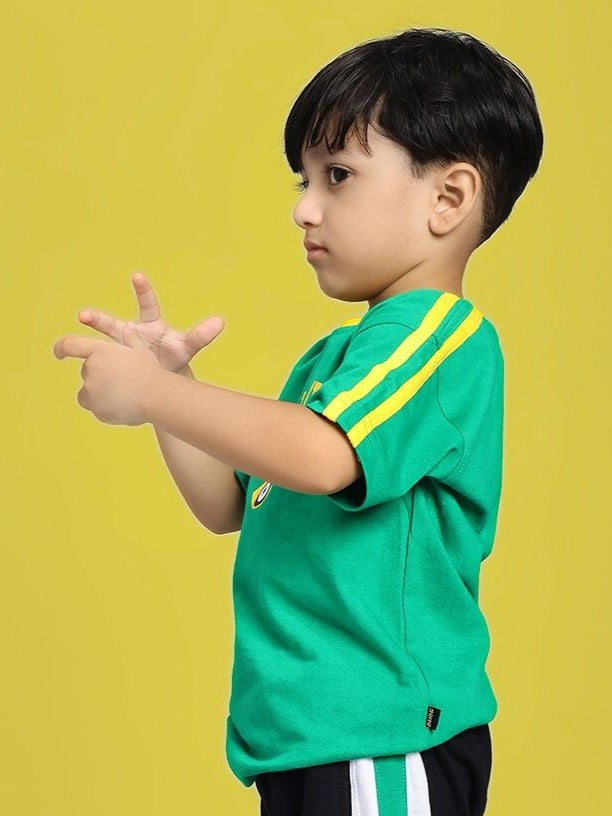 Child wearing IRISH T-SHIRT FOR BOYS AND GIRLS GREEN with yellow stripes on sleeves, standing against a yellow background