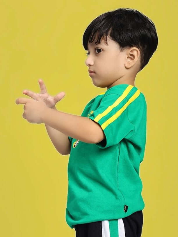 Child wearing IRISH T-SHIRT FOR BOYS AND GIRLS GREEN with yellow stripes on sleeves, standing against a yellow background