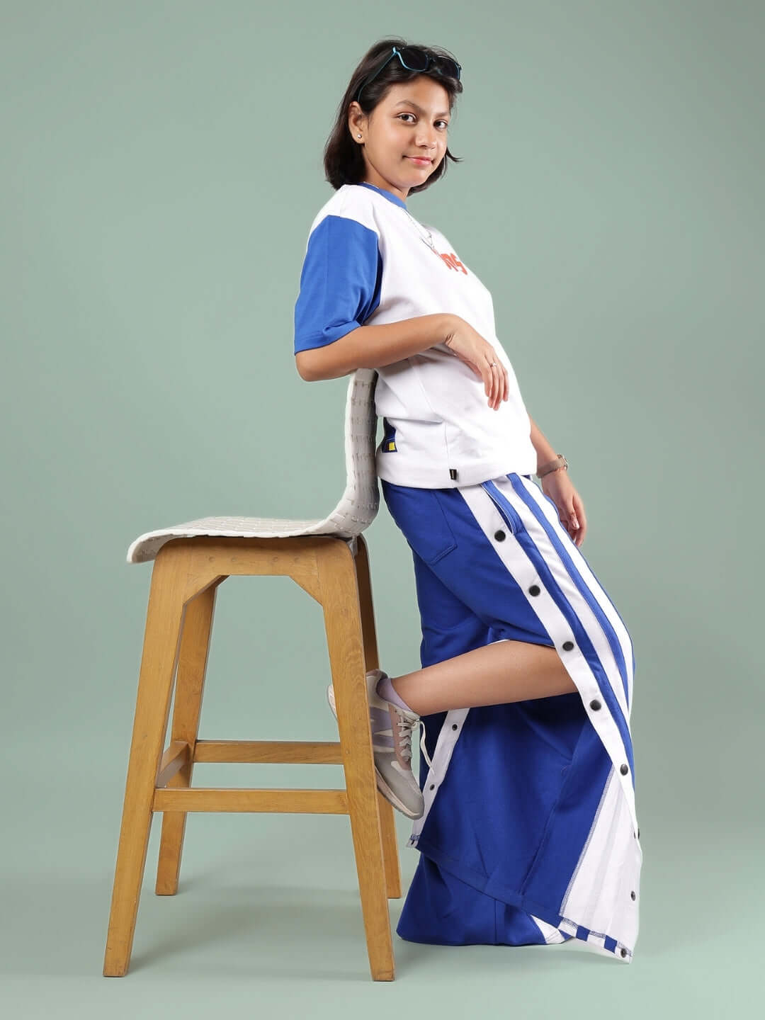 Child wearing IRONA CO-ORD FOR BOYS & GIRLS WHITE-R BLUE set, leaning on a wooden stool, showcasing the stylish design and fit.