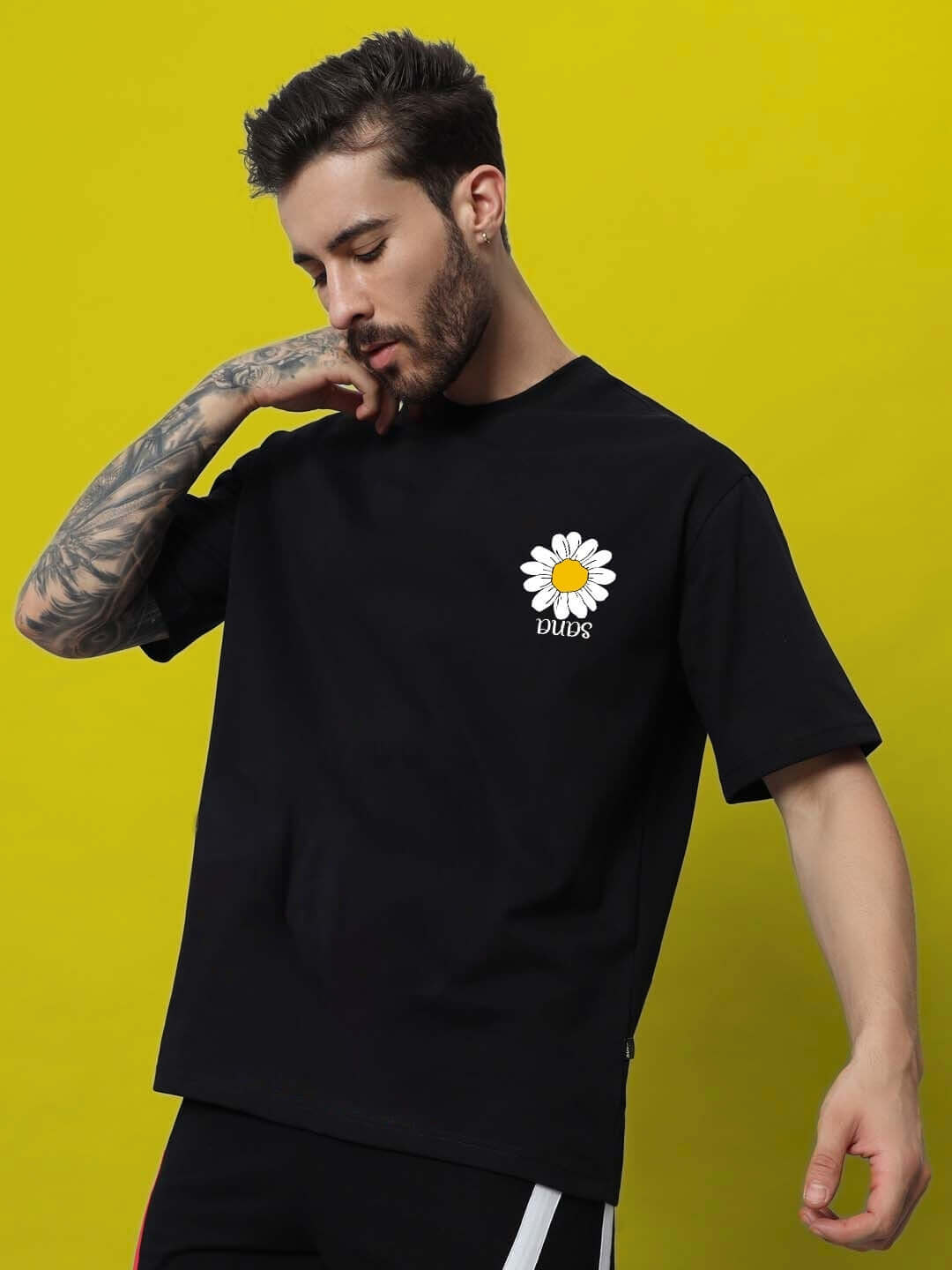 Man wearing IT'S OK PRINTED OVERSIZED T-SHIRT BLACK with daisy print.