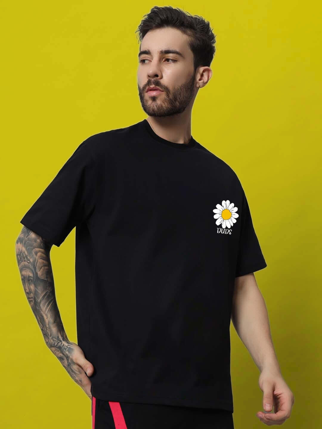 IT'S OK PRINTED OVERSIZED T-SHIRT BLACK featuring a daisy design, worn by a model against a yellow background.