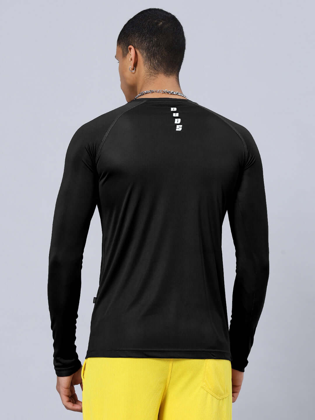 Rear view of JAMES REGULAR FIT T-SHIRT BLACK made from sports polyester fabric, shown on model wearing yellow pants.