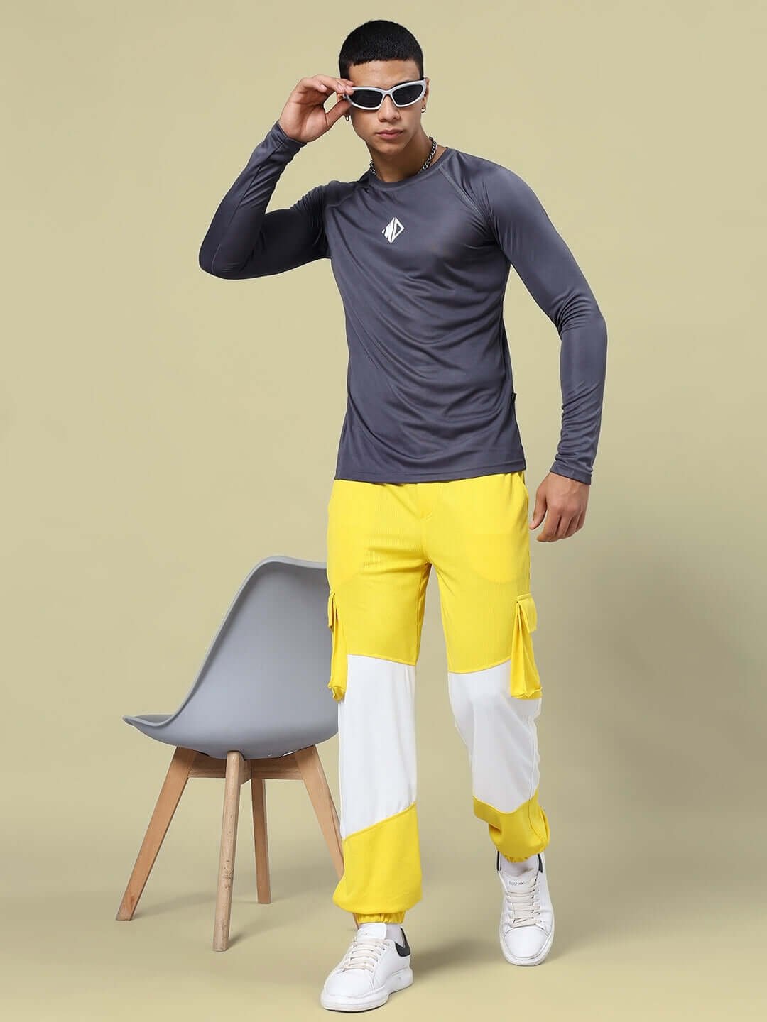 Model wearing JAMES REGULAR FIT T-SHIRT GREY with long sleeves, sports polyester fabric, styled with yellow pants and sunglasses.