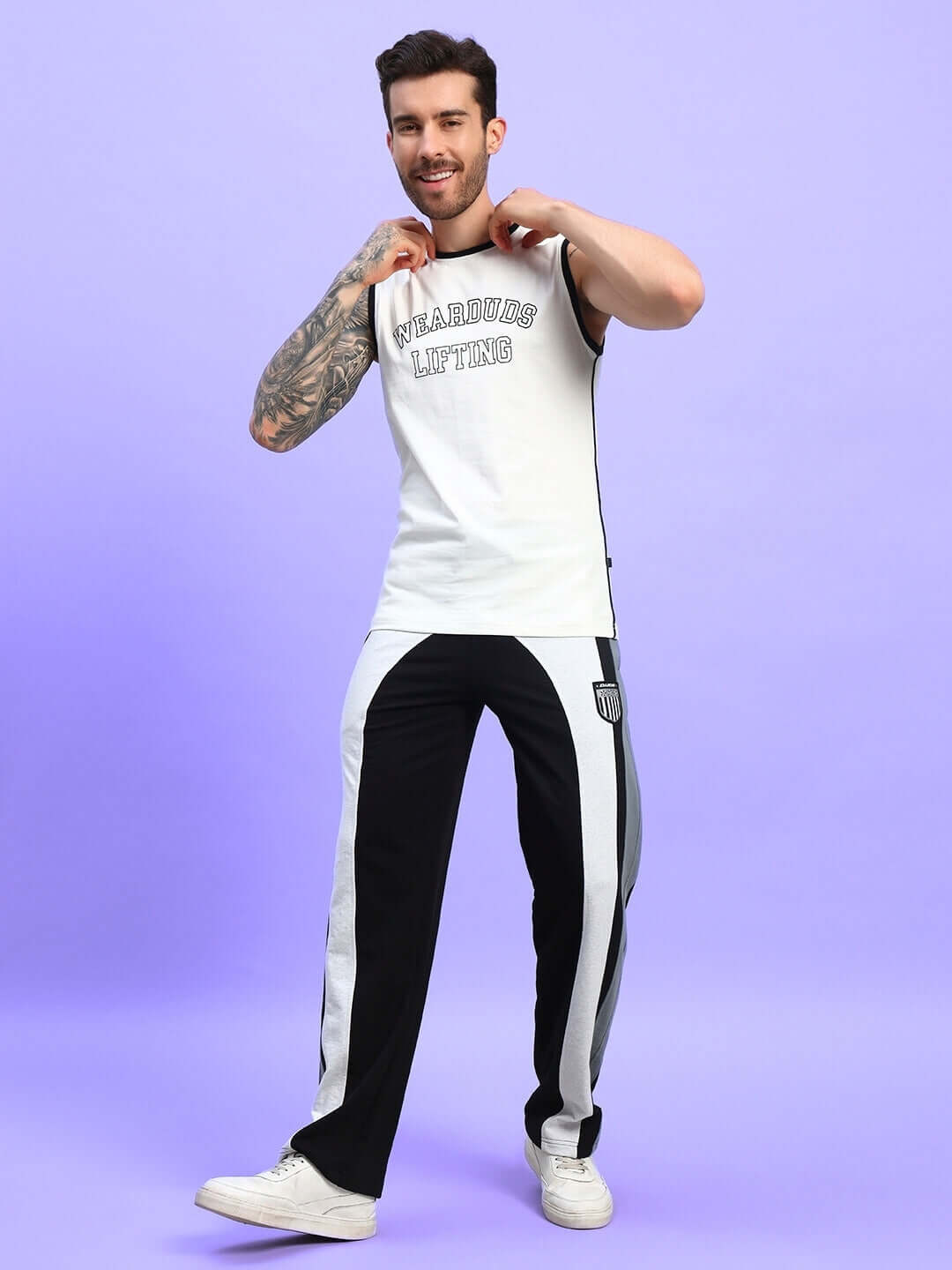 Man wearing Jamison color block relaxed-fit joggers in black melange-grey with a sleeveless shirt on a purple background.