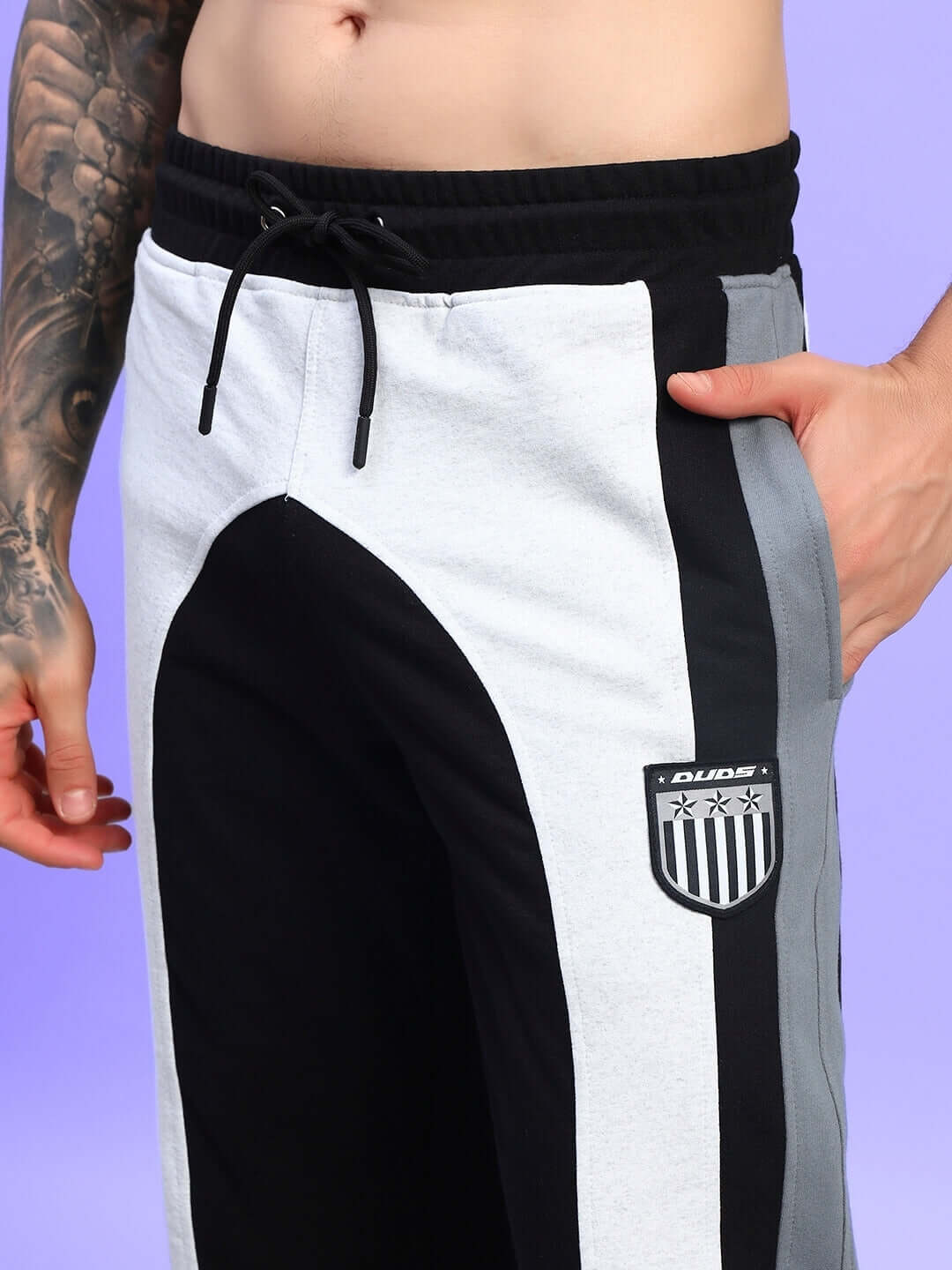 Man wearing Jamison color block joggers in black melange-grey with logo, showcasing relaxed-fit design for comfort and style.