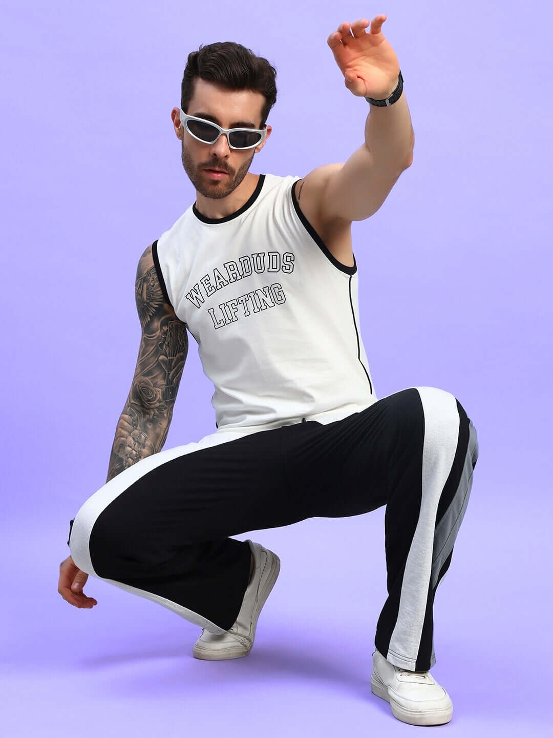 Model wearing Jamison color block joggers in black melange-grey with white stripes, posing stylishly against a purple background.
