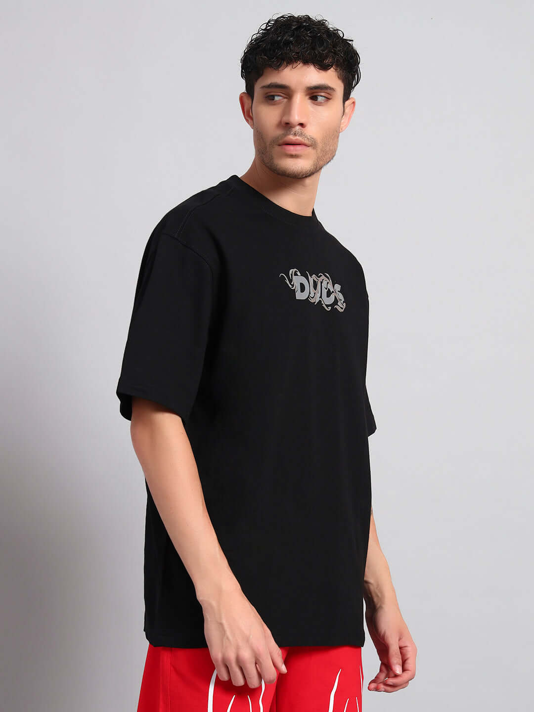 Man wearing JELVIN OVER-SIZED T-SHIRT BLACK, showcasing streetwear style.