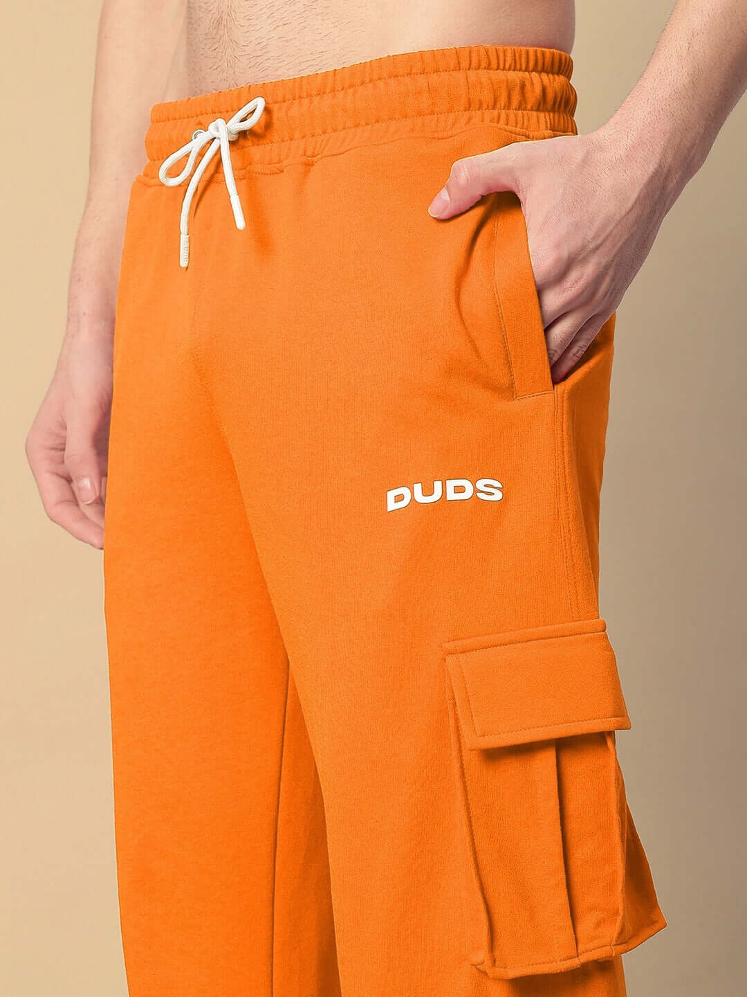 A person wearing orange relaxed fit joggers by DUDS, featuring five pockets and a drawstring waist.