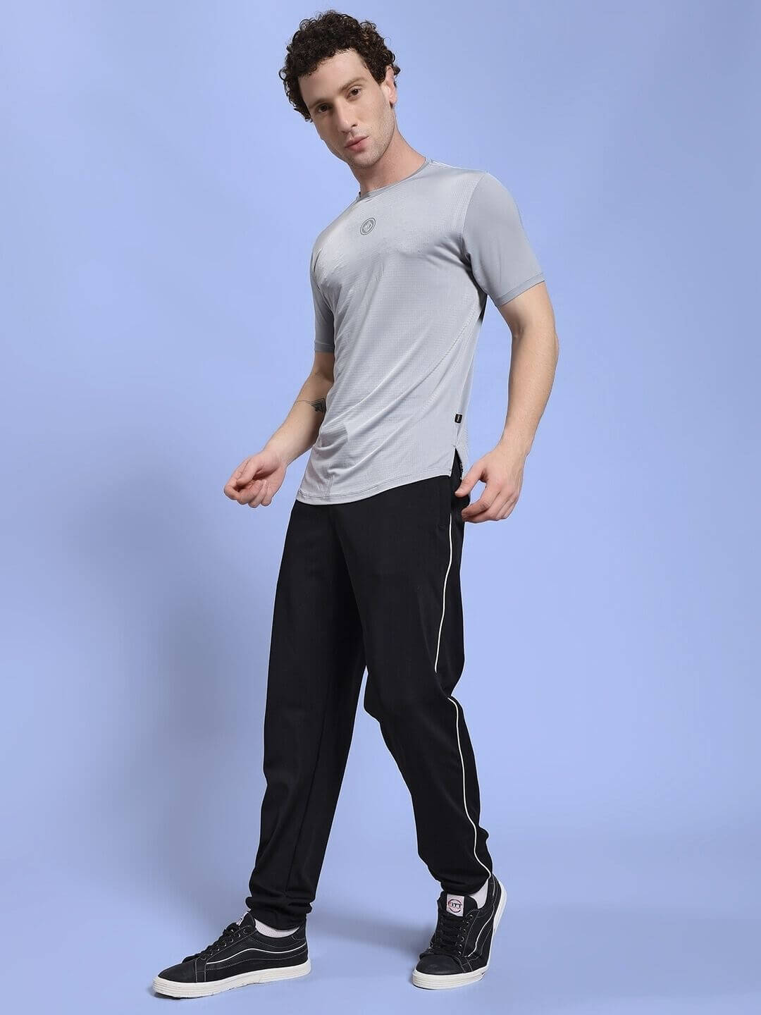 Man wearing JET RUN REGULAR FIT T-SHIRT GREY with black pants, standing against a light blue background.