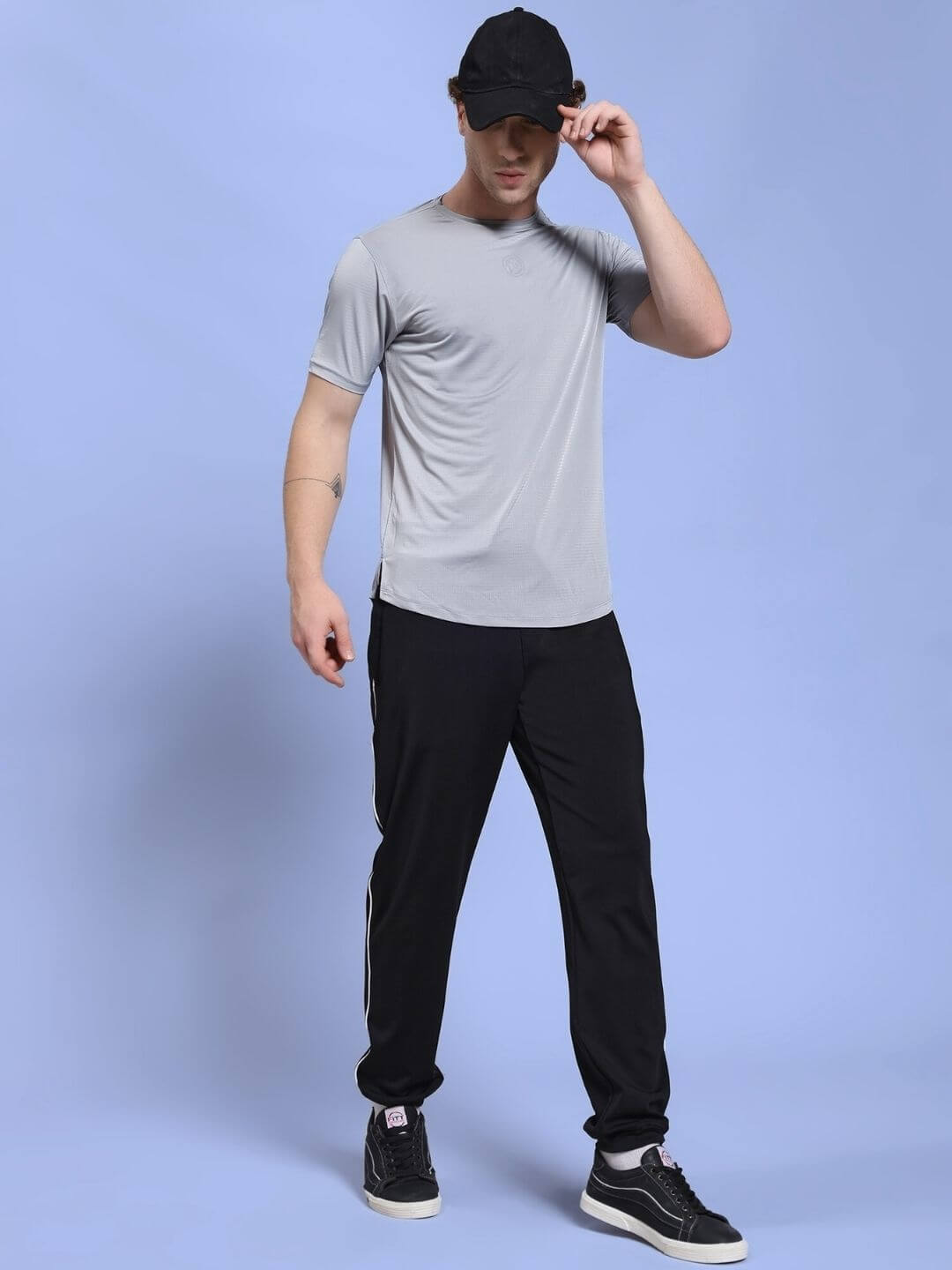 Person wearing a JET RUN REGULAR FIT T-SHIRT GREY paired with black pants and a cap, showcasing casual wear fashion style.