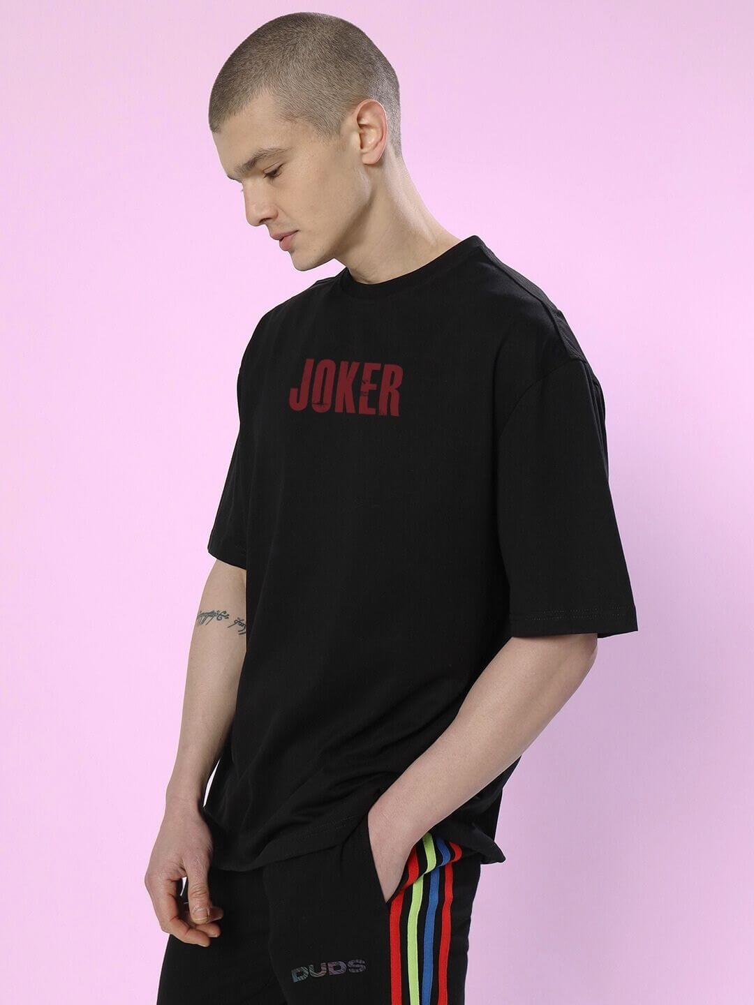 JOKER PRINTED OVERSIZED T-SHIRT BLACK on model, showcasing streetwear style and Joker print in casual setting.