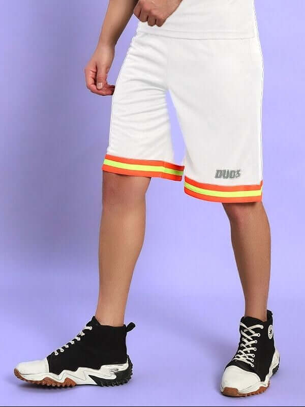 Person wearing JORDAN GYM REGULAR FIT SHORTS WHITE with colorful trim and black sneakers against a purple background.