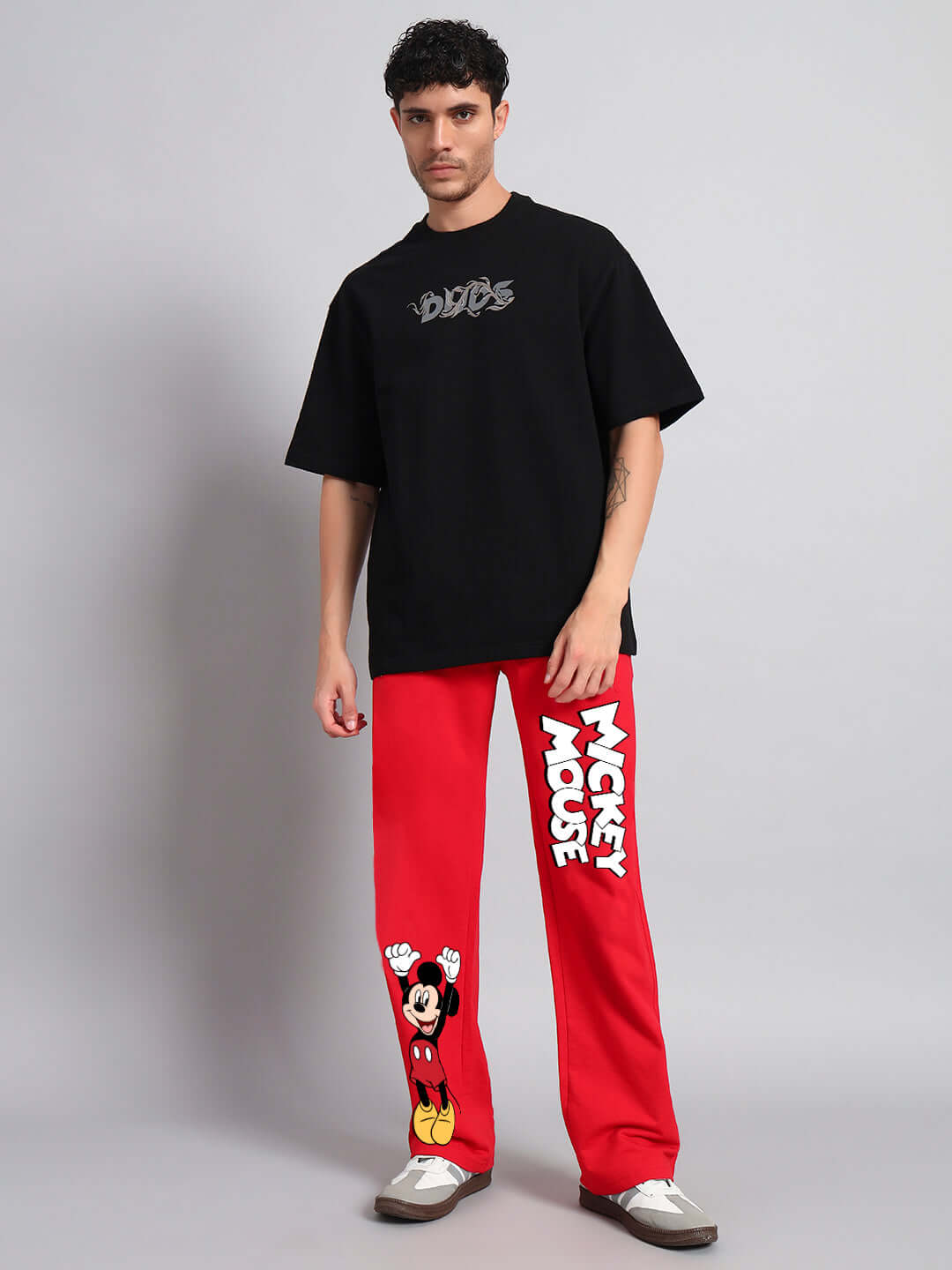 Model wearing JOY FEEL MICKEY RELAXED FIT JOGGER in red with Mickey Mouse print and a black DUDS t-shirt, standing.