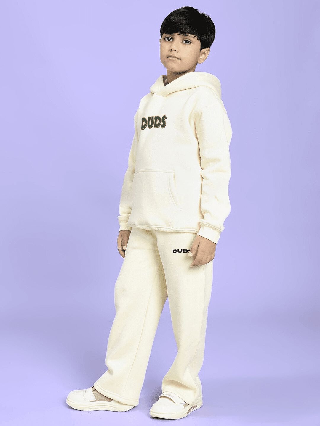 Child wearing JUDY NICK ZOOTOPIA FLEECE CO-ORD FOR BOYS GIRLS OFF WHITE, standing against a purple background.