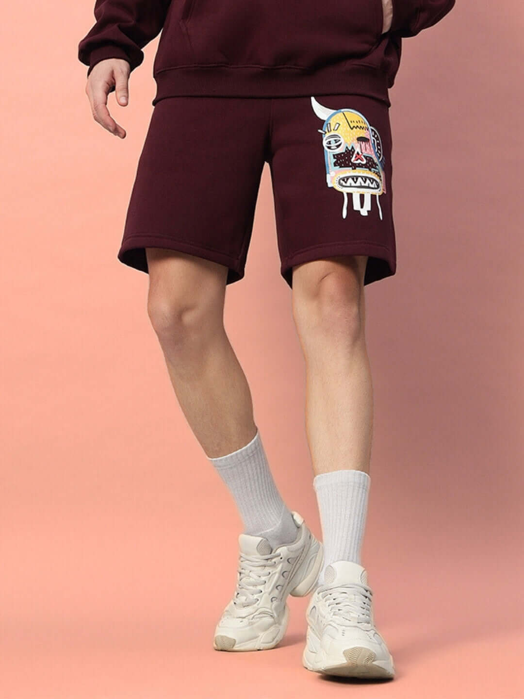 Person wearing WEARDUDS JUMBLED FLEECE SHORTS WINE with colorful design, showcasing trendy and comfortable streetwear fashion.