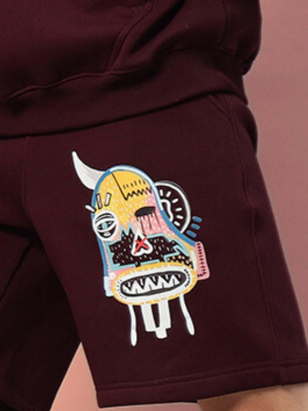 Close-up of WEARDUDS JUMBLED FLEECE SHORTS WINE with colorful graphic design, showcasing trendy streetwear style.