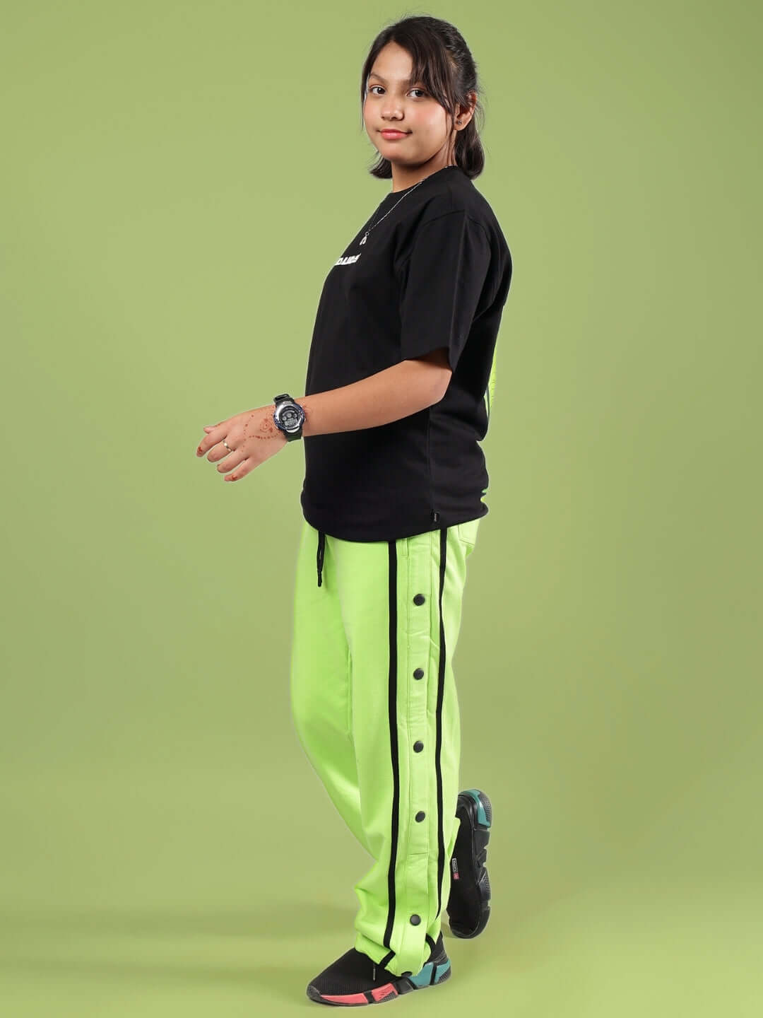 Young model wearing JUMBO CO-ORD FOR BOYS & GIRLS BLACK-NEON set with black top and green pants.