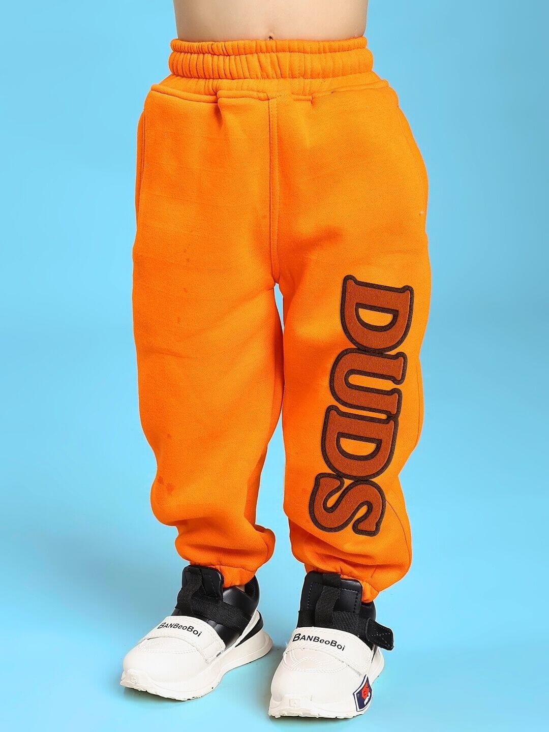 Kid wearing orange pants with 'DUDS' text, displaying the vibrant JUMPYJOY CO-ORD FOR BOYS AND GIRLS WHITE ORANGE style.