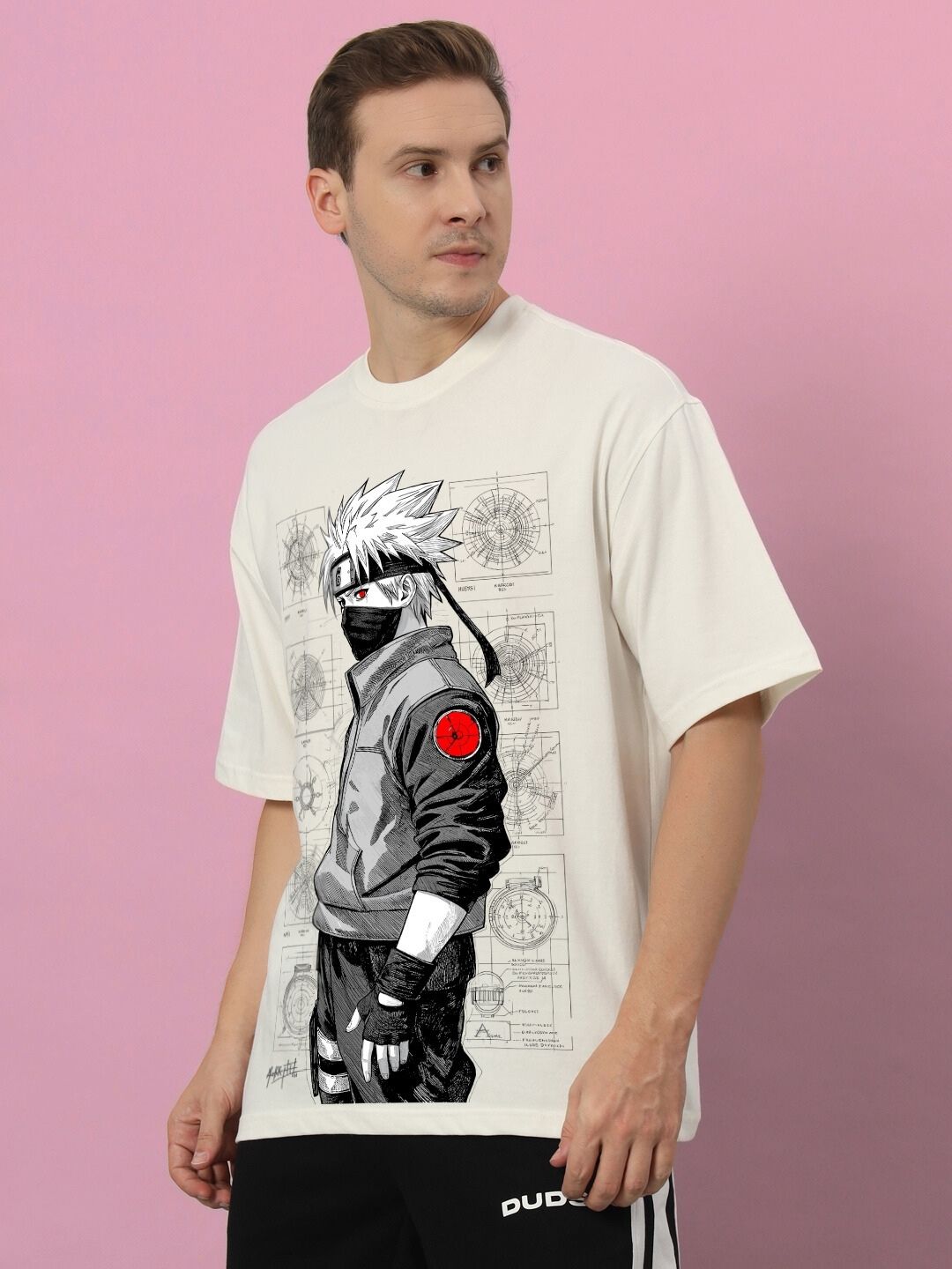 Man wearing KAKASHI PRINTED OVERSIZED T-SHIRT OFF-WHITE, featuring anime graphic design against a pink background.